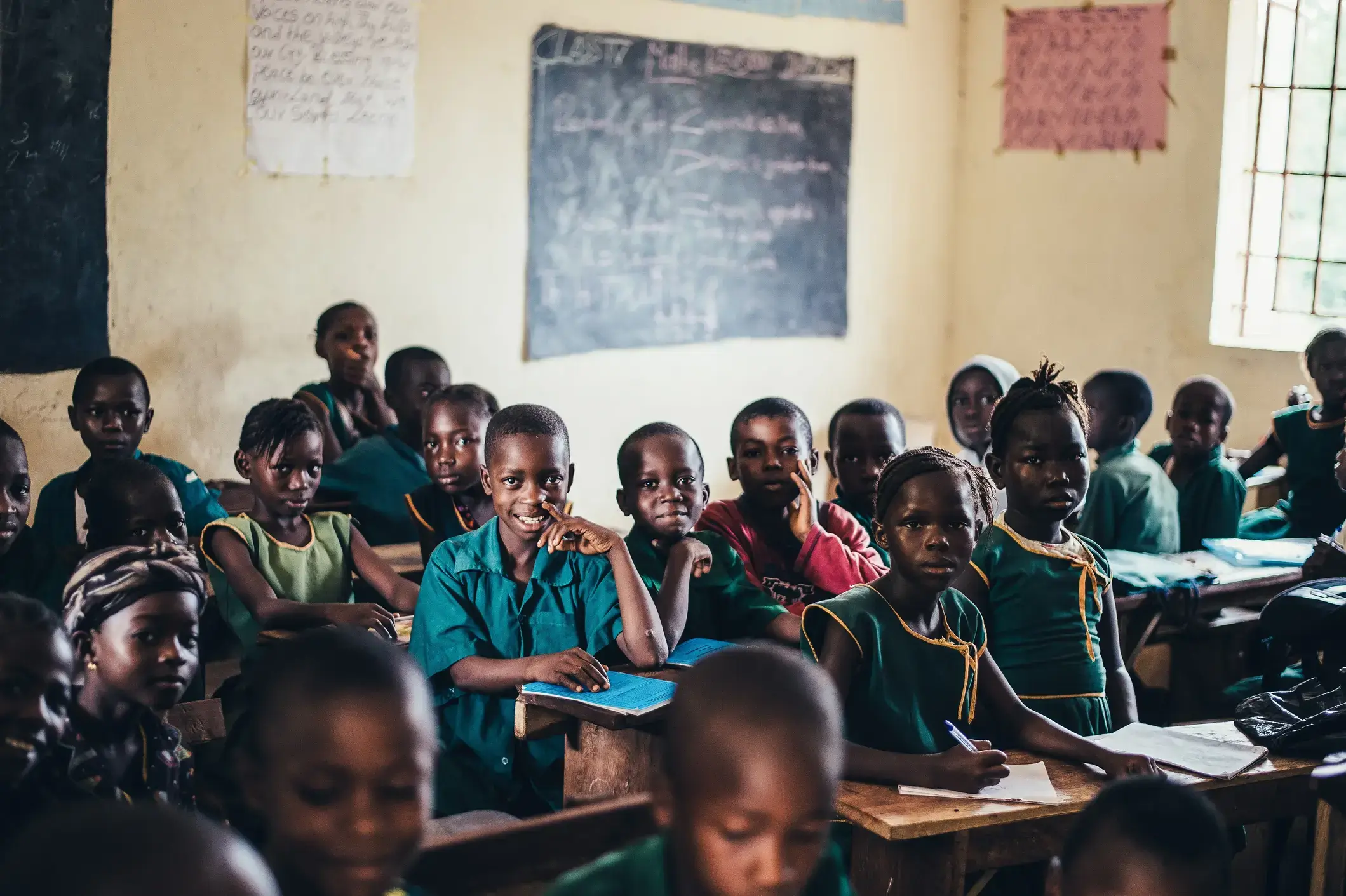 A diverse group of children attentively seated at desks in a bright classroom, engaged in learning activities.